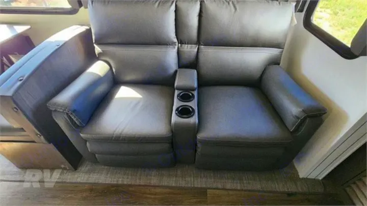Plush grey RV reclining loveseat with central cup holders, ready for your comfortable RV rental.. Keystone RV Cougar 2021