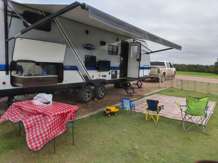 RV rental campsite setup with an open outdoor kitchen, picnic table, chairs, and awning, perfect for outdoor dining.. Jayco Jay Feather 2019
