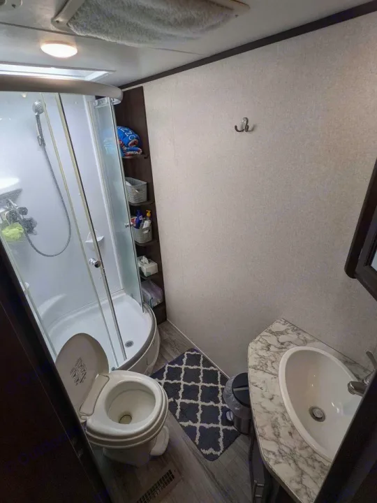 Efficient RV rental bathroom. Features a corner shower, toilet, and small vanity with sink, maximizing space for travel.. Jayco Jay Feather 2019