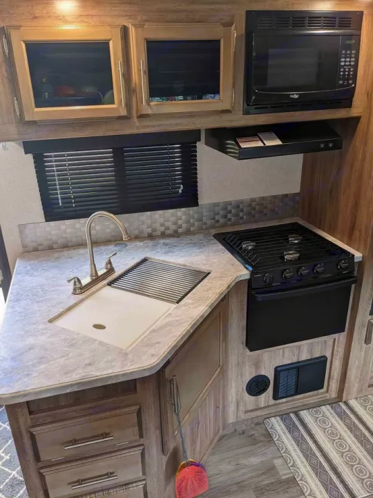 RV rental kitchen: Compact, modern space with sink, stovetop, oven, microwave, and stylish wood cabinetry. Fully equipped.. Jayco Jay Feather 2019