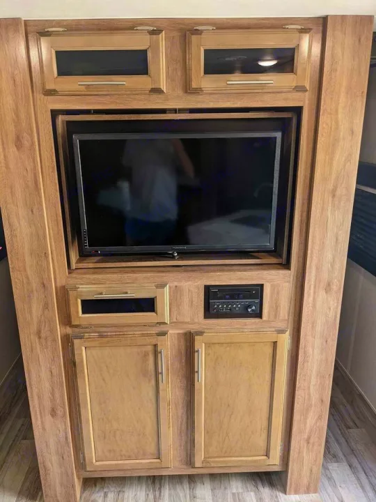 RV rental living space: Integrated entertainment center with TV, stereo, & multiple wood storage cabinets.. Jayco Jay Feather 2019
