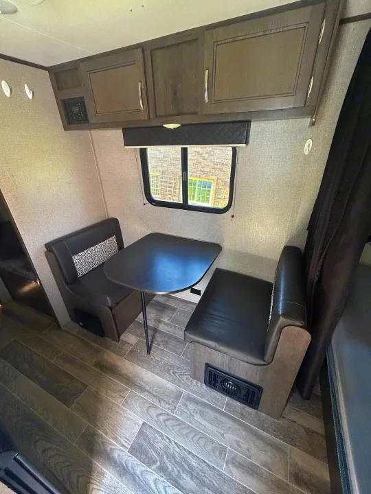 RV rental dinette area with dark seating, table, overhead cabinets, and wood-look flooring.. Jayco Jay Flight SLX 2021