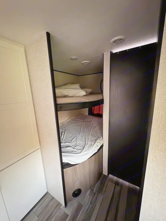 Cozy bunk beds in an RV rental for family camping. Features textured walls & dark floor.. Jayco Jay Flight SLX 2025