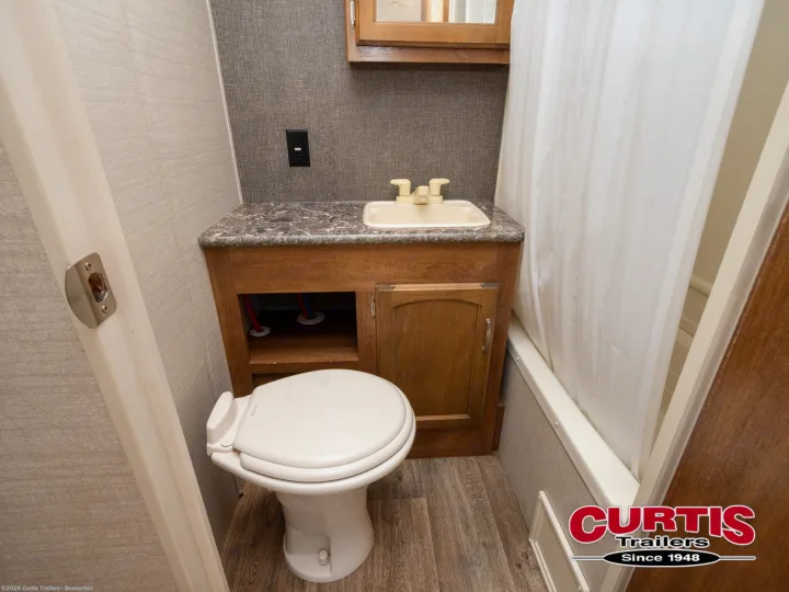 This RV rental's compact bathroom includes a toilet, vanity with sink, and a shower with a white curtain.. Springdale sm2820bh16 2016
