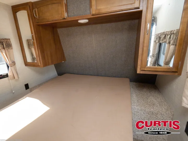 Explore this RV rental's cozy bedroom featuring a comfortable bed, overhead cabinets with mirrors, and ample storage.. Springdale sm2820bh16 2016
