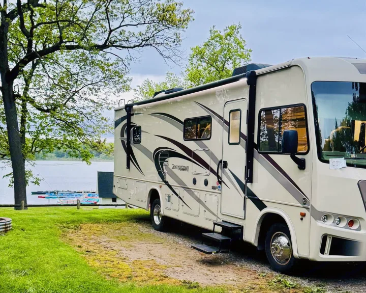 Lakeside rv rental: a white motorhome with extended steps is parked, with docked boats visible in the distance.. Georgetown GT3 2019