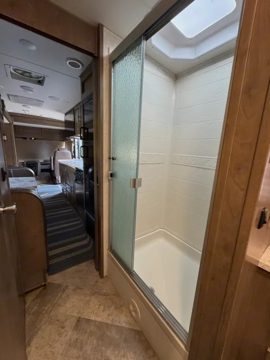 Step inside this RV rental, featuring a clean shower with a textured glass door, and a glimpse of the kitchen and living area.. Georgetown GT3 2019