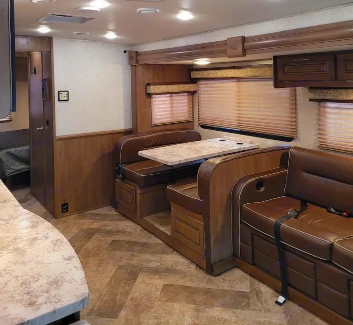 Cozy RV rental interior with brown dinette, sofa with seatbelts, and wood finishes, ready for your road trip.. Georgetown GT3 2019