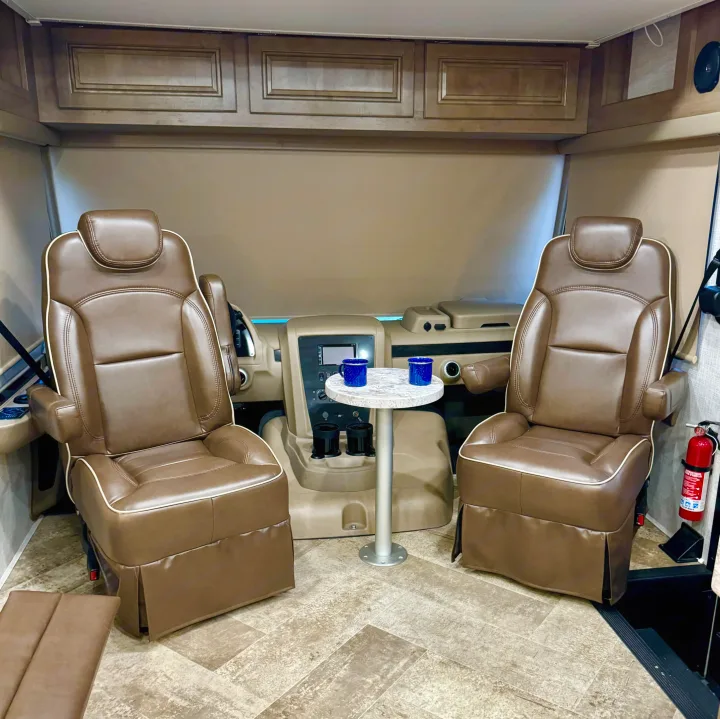 RV rental interior: Front cockpit with two captain's chairs, small table, and overhead cabinets. A cozy mobile home setup.. Georgetown GT3 2019
