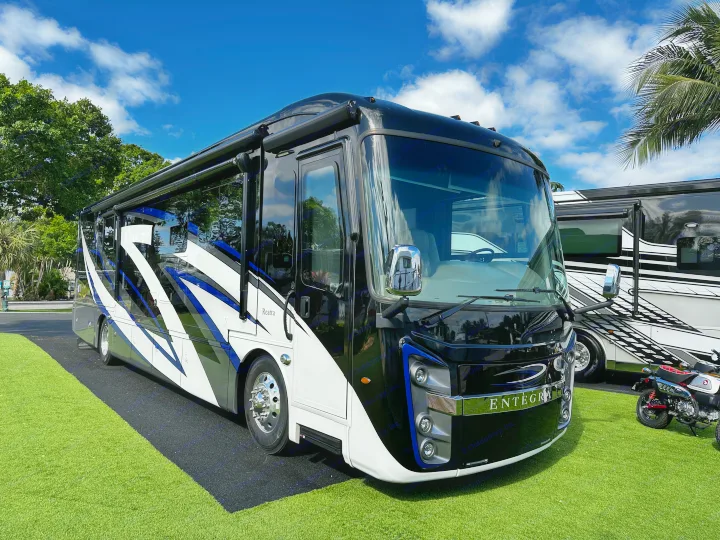 A sleek black & white Entegra Reatta luxury RV, ideal for an unforgettable RV rental experience, parked on green turf.. Entegra Coach Reatta 2021
