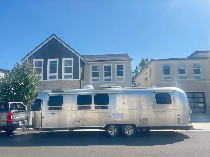 A classic silver Airstream travel trailer hitched to a large pickup truck. Perfect RV rental for your next road trip adventure!. Airstream Classic 2012