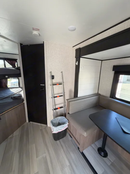 This RV rental features a cozy dinette with seating & table, bunk beds, and durable wood-look flooring for travel comfort.. Autumn Ridge 188BHS 2025