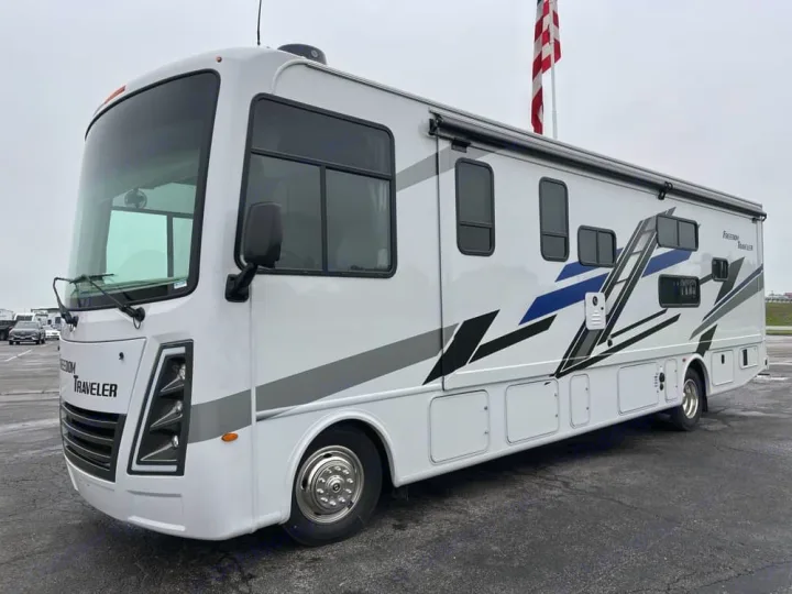 Spacious white Freedom Traveler RV rental, featuring striking blue and gray side graphics, parked outdoors.. Thor Freedom Traveler 2025