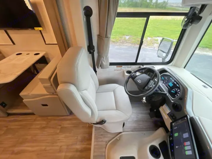 Modern RV rental interior: spacious driver's cabin with dashboard, steering wheel, comfortable seating, and dining area.. Thor Freedom Traveler 2025