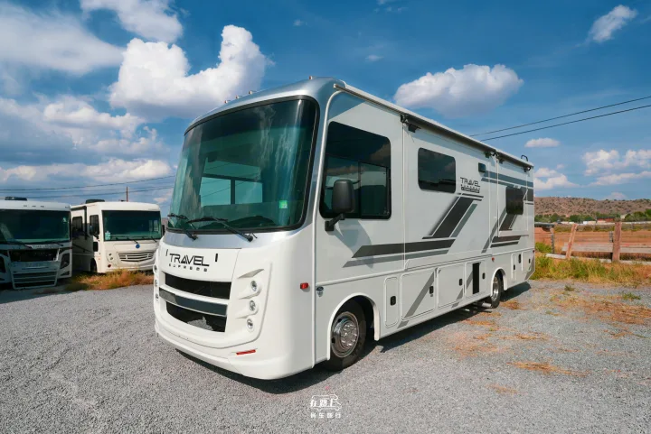 A modern "TRAVEL SUPREME" RV rental is parked on a gravel lot under a blue sky, ready for your next adventure.. Jayco Travel Supreme A Series 27A 2025