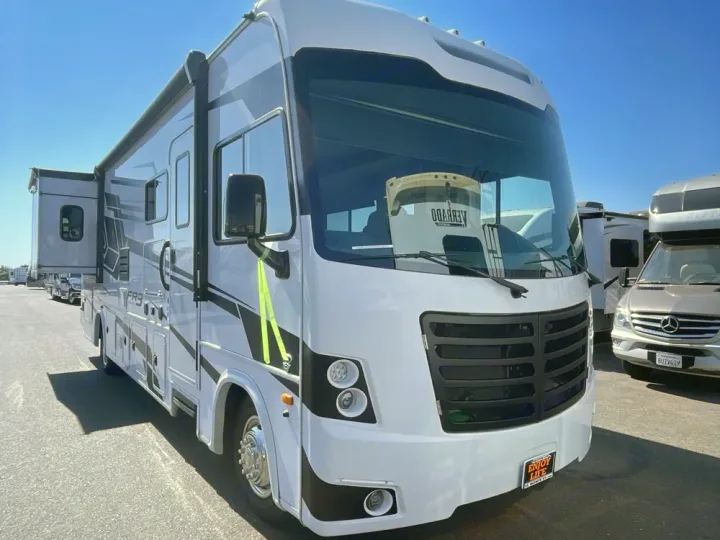 White Class A motorhome RV rental with extended slide-out and awning, parked outdoors in bright sunlight.. FR3 FR3 Motorhome 2024