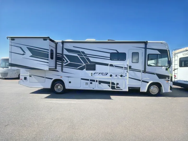 White Forest River FR3 RV rental with extended slide-out and bold black/grey geometric graphics, parked under clear skies.. FR3 FR3 Motorhome 2024