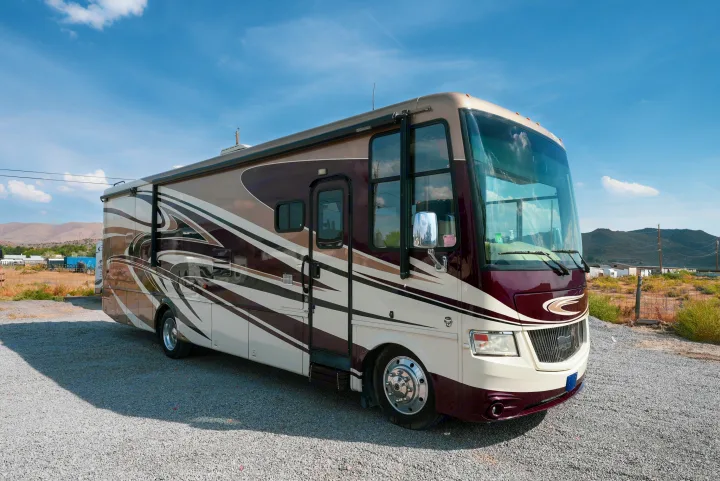 This spacious brown and maroon Class A RV rental is parked on a gravel lot, ready for your travel adventures across scenic routes.. Newmar Canyon Star 3424 2014