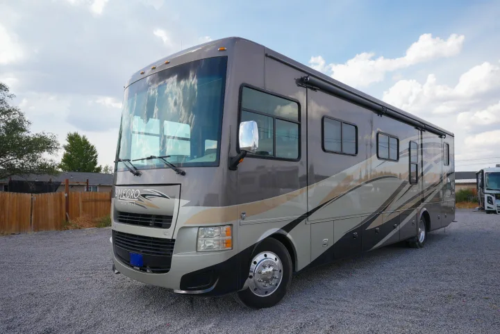 This large Allegro motorhome, ideal for an rv rental, is parked on a gravel lot under a cloudy sky.. Allegro Allegro Motorhome 2014