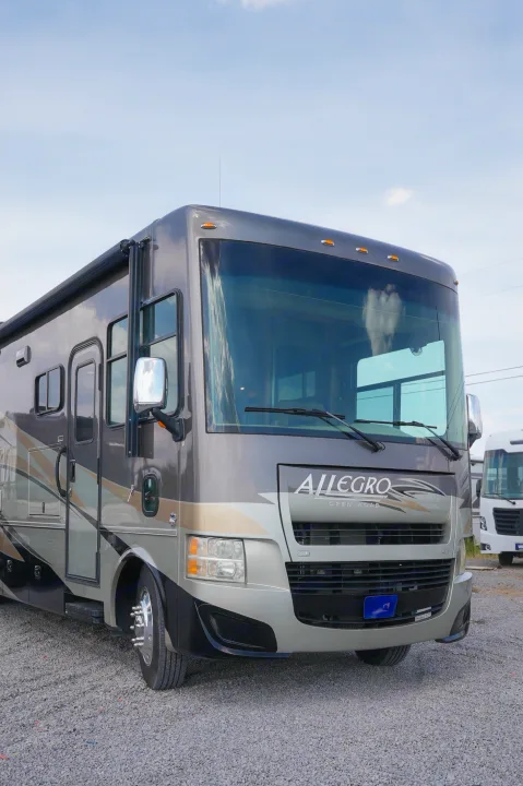 Up-close view of a stylish gray & beige Allegro Class A RV rental on gravel, perfect for your next motorhome adventure.. Allegro Allegro Motorhome 2014