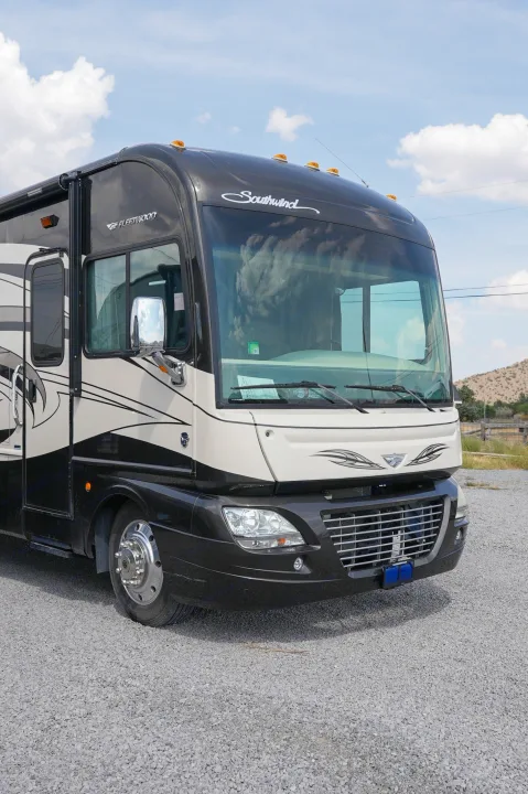 This large black and cream Fleetwood Southwind RV rental is a spacious motorhome, parked on gravel ready for adventure.. Southwind Southwind Motorhome 2013