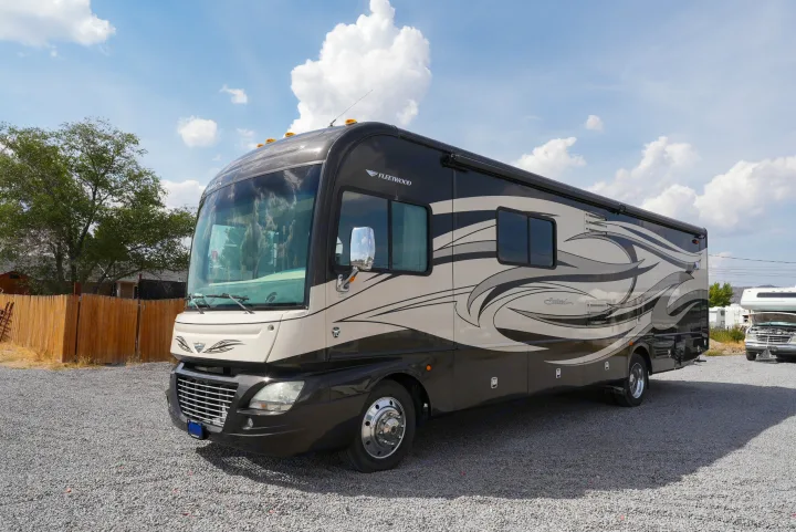 Spacious Fleetwood Southwind RV rental, a black and tan motorhome with swirling graphics, parked on a gravel lot under a blue sky.. Southwind Southwind Motorhome 2013