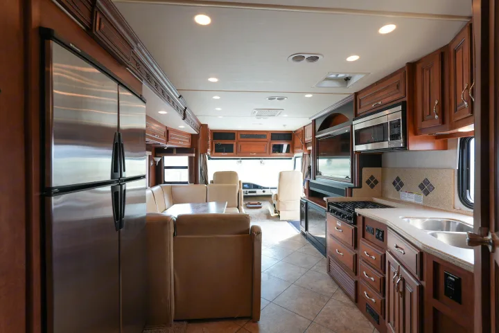 Spacious RV rental interior featuring a full kitchen with stainless steel appliances, a comfortable dining booth, and front cockpit.. Southwind Southwind Motorhome 2013