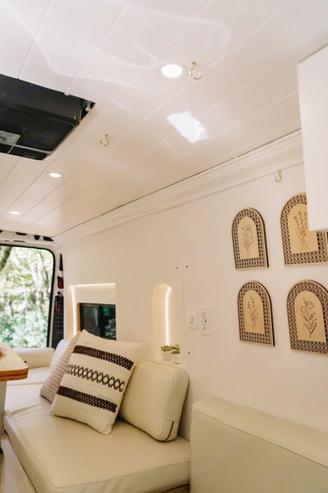 Bright RV rental living space featuring cream seating, wooden floral decor, recessed lighting, and a nature view.. Ram ProMaster 3500 2024