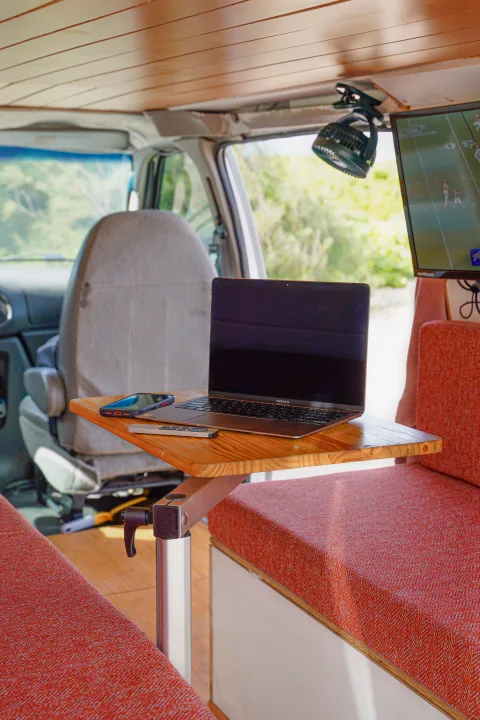 RV rental: Modern van interior featuring a laptop workstation, TV for entertainment, and fan, ideal for mobile living.. Ford Econolline 250s 2005