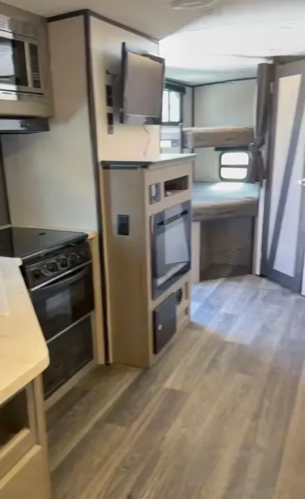Modern rv rental interior with kitchen (stove, microwave), TV, electric fireplace, and bunk beds.. Heartland RVs Mallard 2021