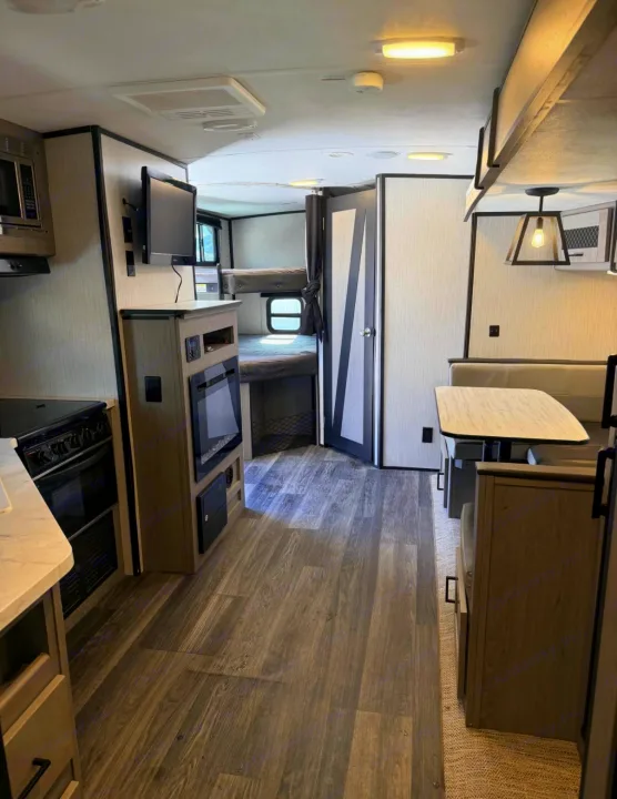 Modern rv rental interior with full kitchen, dining booth, cozy fireplace, and bunk beds. Ready for your next adventure!. Heartland RVs Mallard 2021