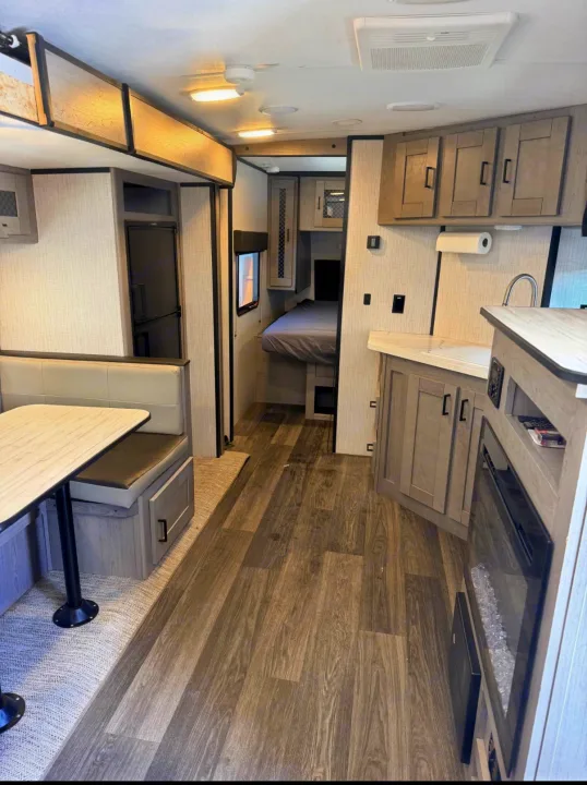 This rv rental interior features a dinette, a compact kitchen with a sink and refrigerator, and a cozy bedroom area.. Heartland RVs Mallard 2021