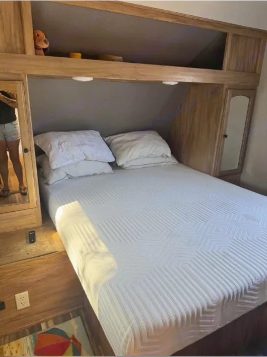 Experience comfort in this RV rental bedroom: full bed with geometric quilt, ample storage, and mirrored cabinets. Ready for travel!. Coachmen Freedom Select Express 28.7 2019