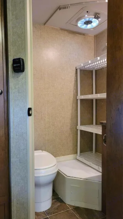 This RV rental bathroom features a compact toilet, shower stall with shelves, and ceiling fan/vent.. Spree Escape 2016