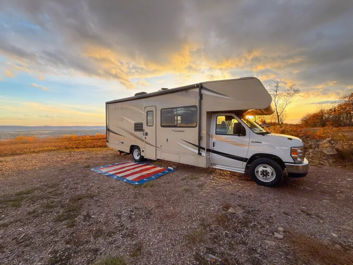Stunning RV rental at sunset. A Coachmen motorhome parked with an American flag mat, overlooking a beautiful valley.. Coachman Leprechaun 2019