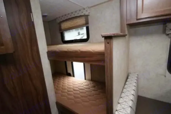Interior of an RV rental featuring cozy bunk beds with quilted mattresses and a window, providing extra sleeping space for travelers.. Coachmen Viking 2017
