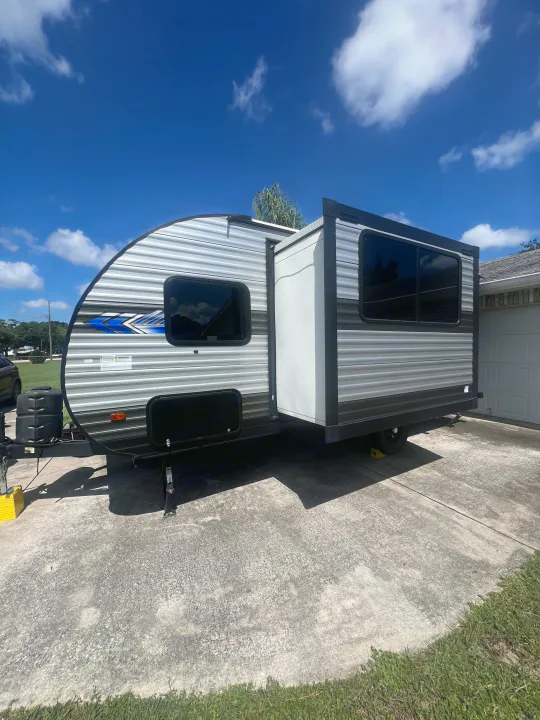 Bright sunny day with a silver and black travel trailer RV rental, extended slide-out, parked on a driveway. Ready for travel.. Forest River Salem FSX 2023