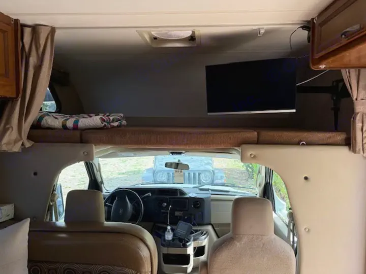 Cozy rv rental interior, featuring an overhead bunk bed, mounted TV, and front cabin view. Perfect for camper adventures.. Thor Freedom Elite 2015