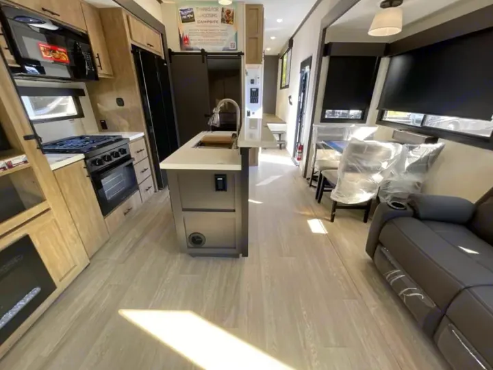 Spacious rv rental interior: well-equipped kitchen with island, dining table with covered chairs, & recliners. Light wood floors.. FOREST RIVER Campsite Elite 36RF 2026