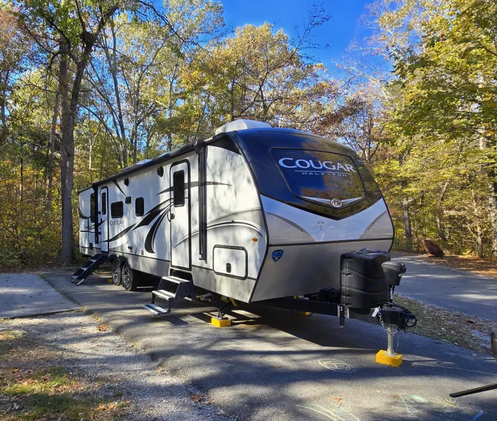 This Cougar RV rental travel trailer is perfectly set up at an autumn campground under clear blue skies, ready for your adventure.. Keystone RV Cougar 2022