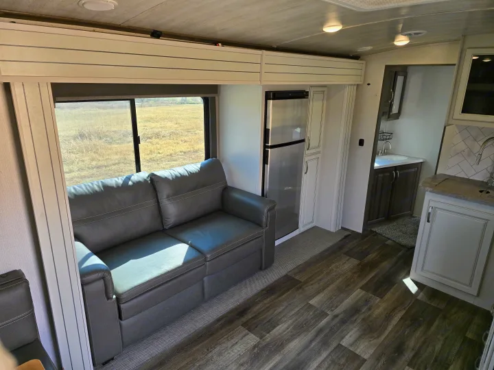Modern RV rental interior with spacious living area, sofa, kitchen, and bath.. Keystone RV Cougar 2022