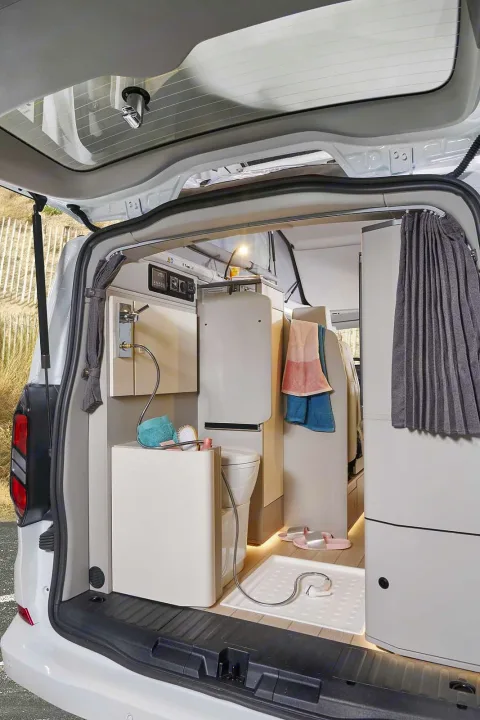 Compact RV rental camper van interior: rear view shows a toilet, sink, and portable shower setup for travel convenience.. Westfalia Kelsey 2024