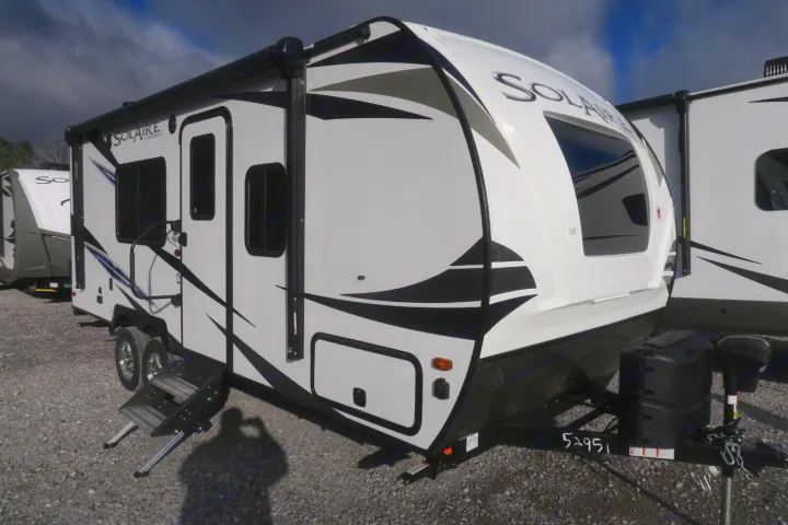 White Solaire travel trailer, ideal for RV rental adventures. Features black graphics, awning, and entry steps.. Forest River Palomino Solaire 2021