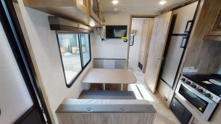 This RV rental features a dinette, kitchen with stove and fridge, and a TV. Light wood interior for comfortable travel.. Forest River Palomino Solaire 2021