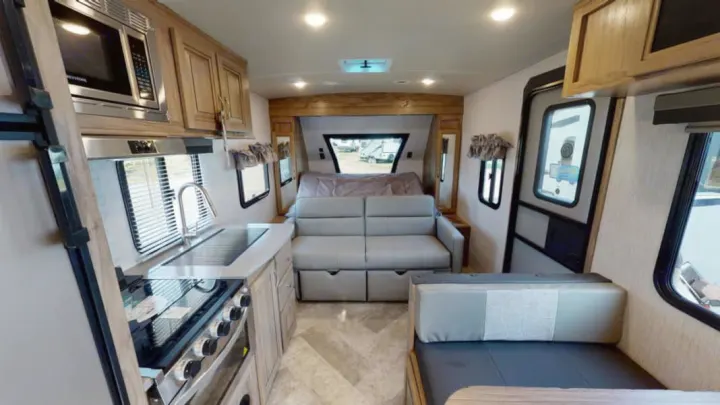 View inside an rv rental, showcasing a modern kitchen, comfortable sofa, and dining area for travel.. Forest River Palomino Solaire 2021