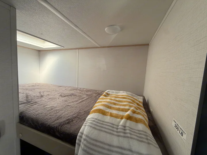 RV rental interior featuring a cozy bunk bed with soft blankets and a 250 LB capacity.. Forest River Avenger LT 2025