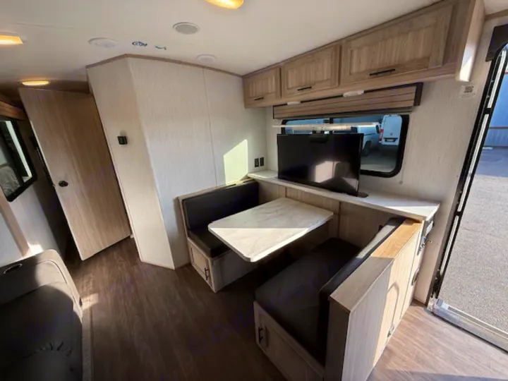 Inside this RV rental, a compact dinette with table & TV, wood-look flooring, and overhead cabinets offer a comfortable travel space.. Cruiser RV Shadow Cruiser 248RKS 2022