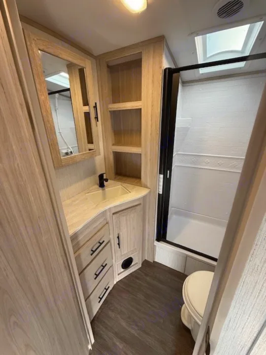 RV rental bathroom: compact layout with a walk-in shower, sink, toilet, mirror, & light wood-look cabinets for storage.. Cruiser RV Shadow Cruiser 248RKS 2022