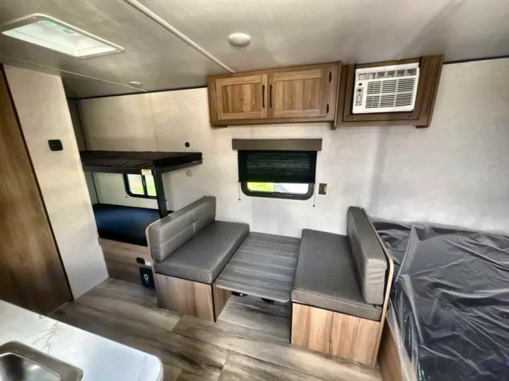 Spacious rv rental interior featuring bunk beds, a dinette, main sleeping area, and air conditioner. Ready for your adventure!. Heartland RVs Prowler 2022