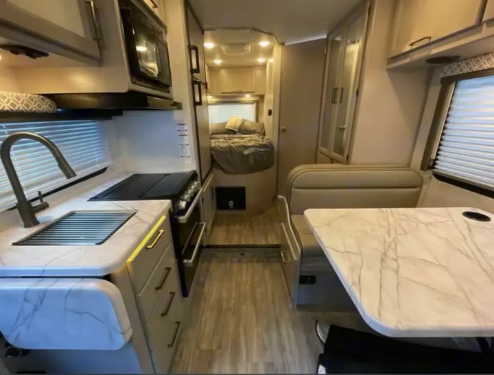 This RV rental's modern interior features a full kitchen, dining booth, and comfy bed, perfect for travel.. Thor Freedom Elite 2026